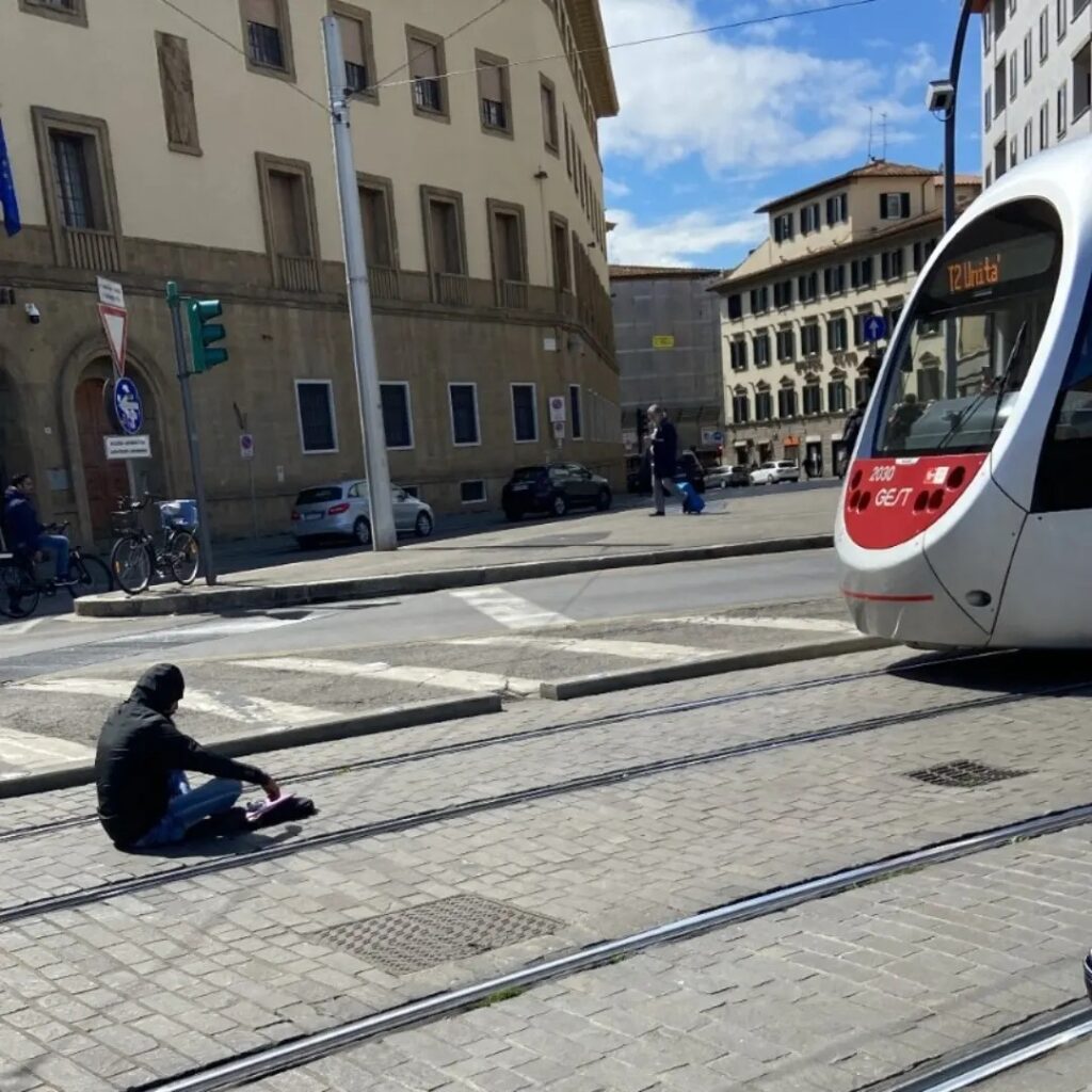 Persona seduta sui binari della tramvia